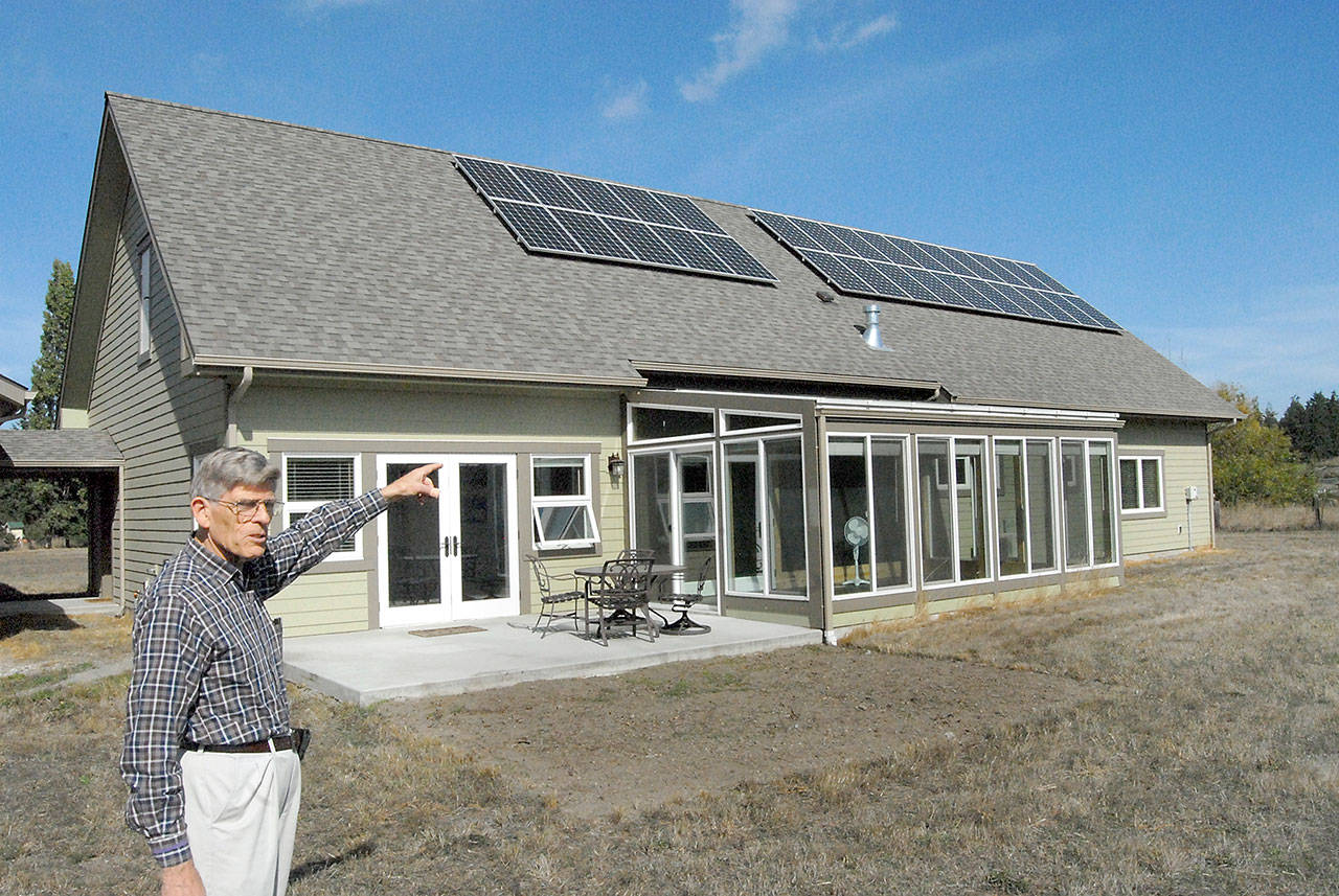 David Large points out a solar panel array and a glass-enclosed sun room that provide electricity and heat to his energy efficient home in rural Sequim, seen here in September 2018. (Keith Thorpe/Peninsula Daily News)