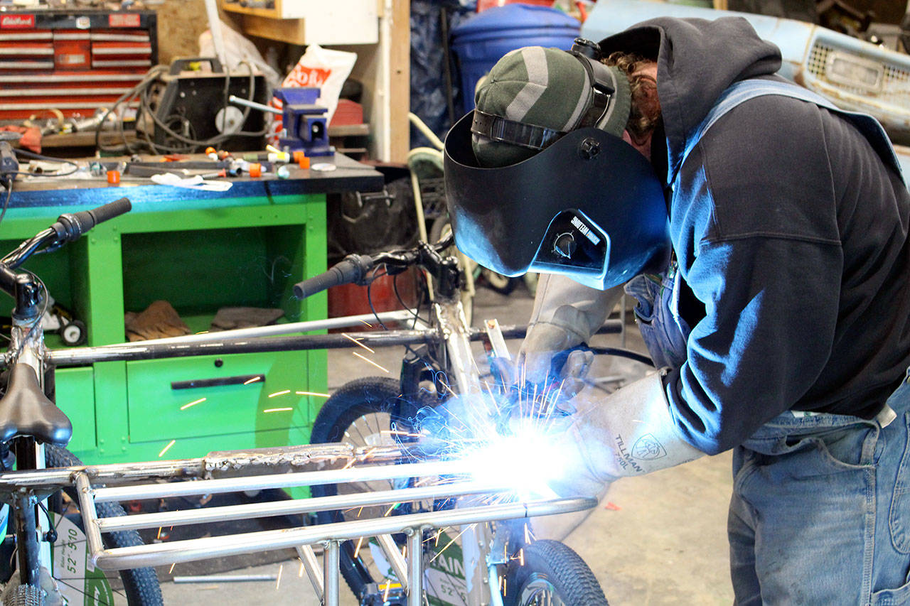Kinetic Race pilot Collin Bertl works on the welds of his sculpture for this weekend’s Kinetic Sculpture Race. Due to the thin metal, Bertl has to weld in small portions, so as to not burn through the metal. (Zach Jablonski/Peninsula Daily News)