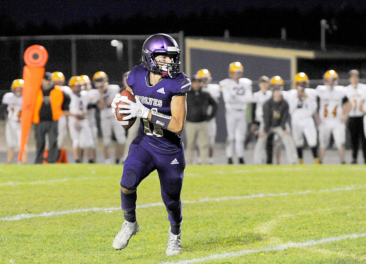 Sequim’s Michael Young looks for an open receiver to complete a two-point conversion following a first half touchdown in Sequim’s 44-14 win over Kingston Friday night. Young ran the ball in for the conversion. (Michael Dashiell/Olympic Peninsula News Group)