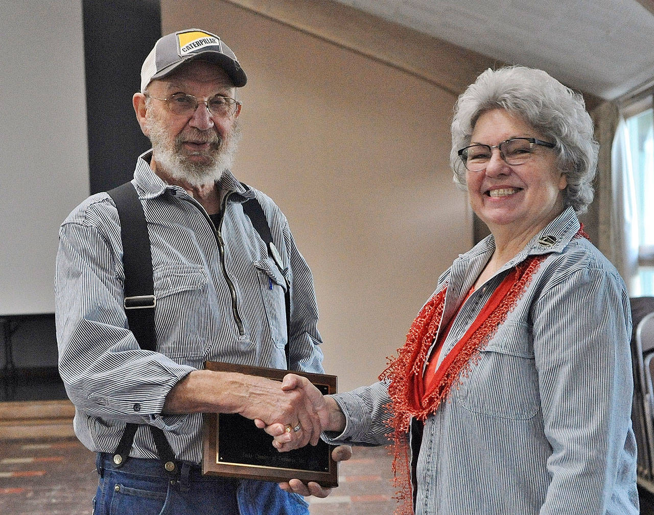 Forks Timber Museum director Linda Offutt presents Richard Halverson with the Pioneer Logger award at the West End Business & Professional Association meeting Wednesday at the Forks Congregational Church. (Lonnie Archibald/for Peninsula Daily News)