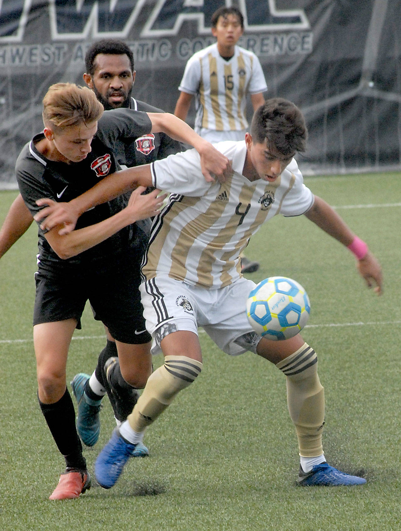 Keith Thorpe/Peninsula Daily News Peninsulas Isael Lopez-Plascencia, right, fends off Everetts Aiden Cook as Cooks teammate, Nahor Asso, comes up from behind on Saturday at Wally Sigmar Field in Port Angeles.