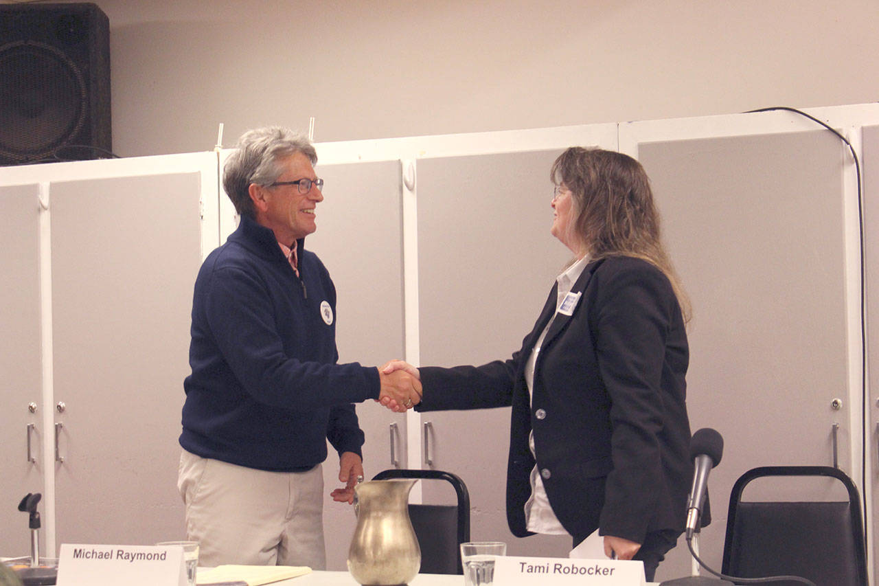 Chimacum School Board, District 4, candidates Michael Raymond, left, and Tami Robocker shake hands after completing their portion of the candidate forum hosted by the League of Women Voters at the Tri-Area Community Center for the six school board candidates. (Zach Jablonski/Peninsula Daily News)
