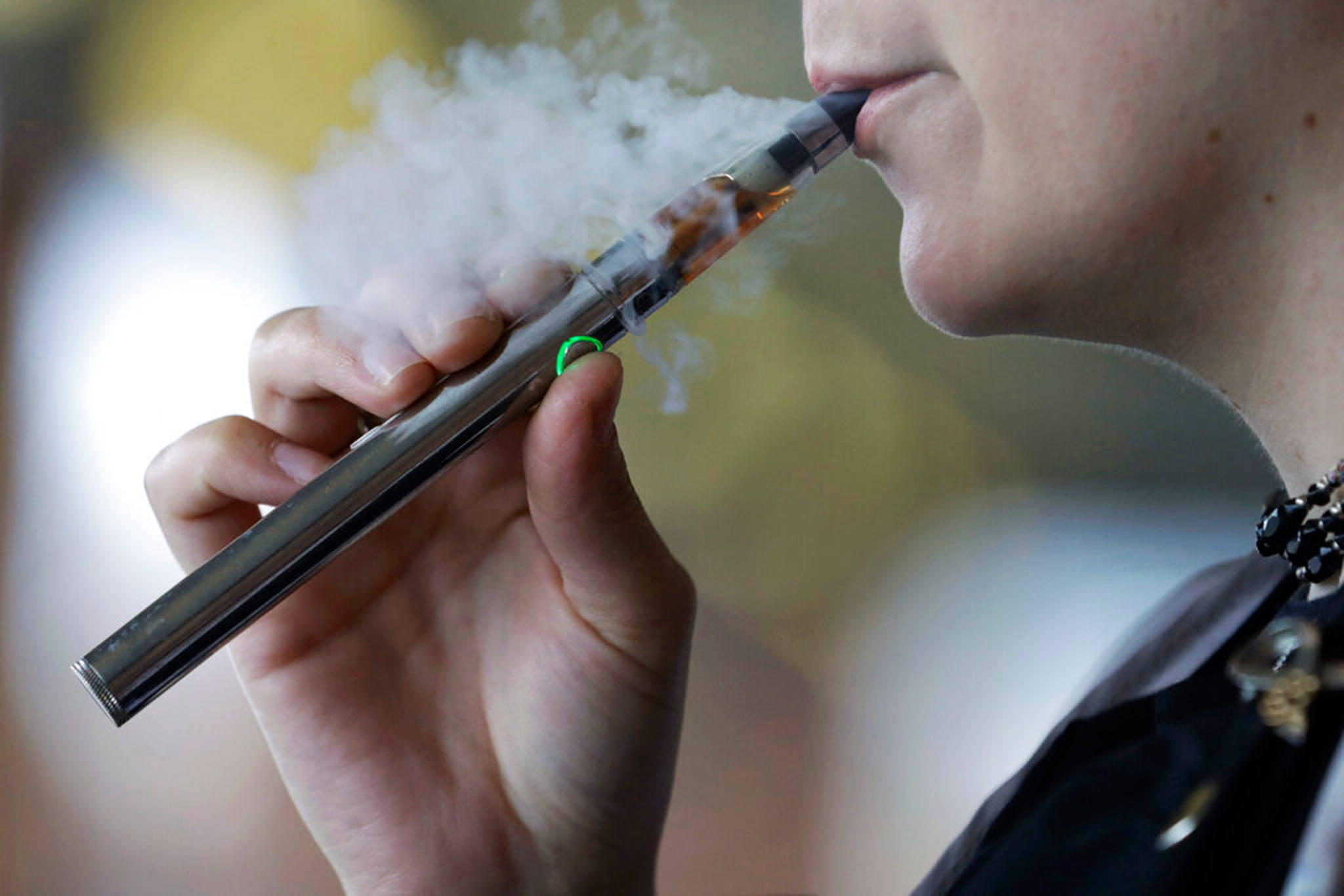In this Oct. 4, 2019 file photo, a woman using an electronic cigarette exhales in Mayfield Heights, Ohio. Washington health officials are issuing a bulletin to Clallam and Jefferson county doctors, informing them that they are now required to report if anyone is diagnosed with a mysterious vaping-related lung illness. (AP file photo/Tony Dejak)