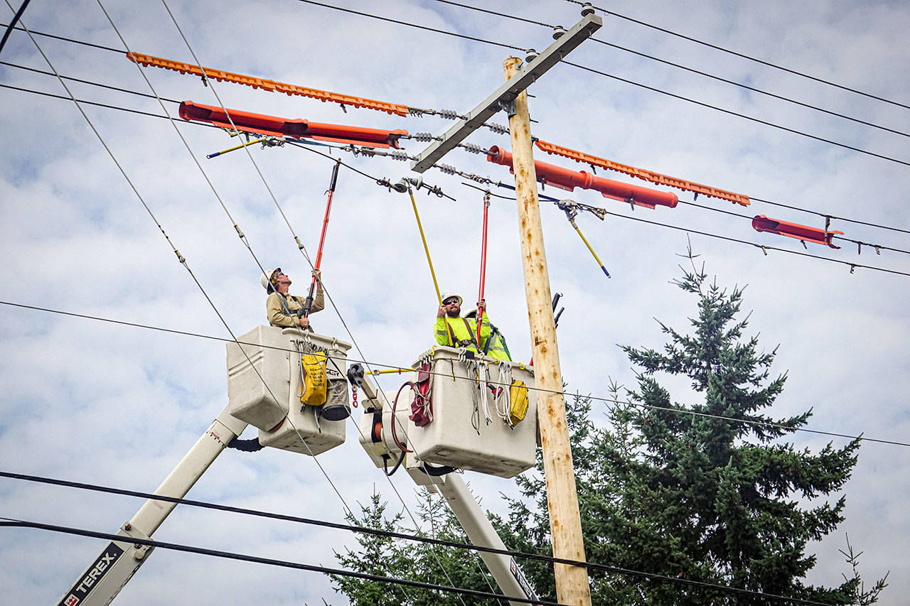 Kurt Anderson, left, and Dylan Brackney, Jefferson County Public Utility District journeyman linemen, install new switching on distribution lines outside the Hastings Substation on Sheridan Street in Port Townsend recently. The switching allows linemen to redirect power during an outage. (Jefferson County PUD)