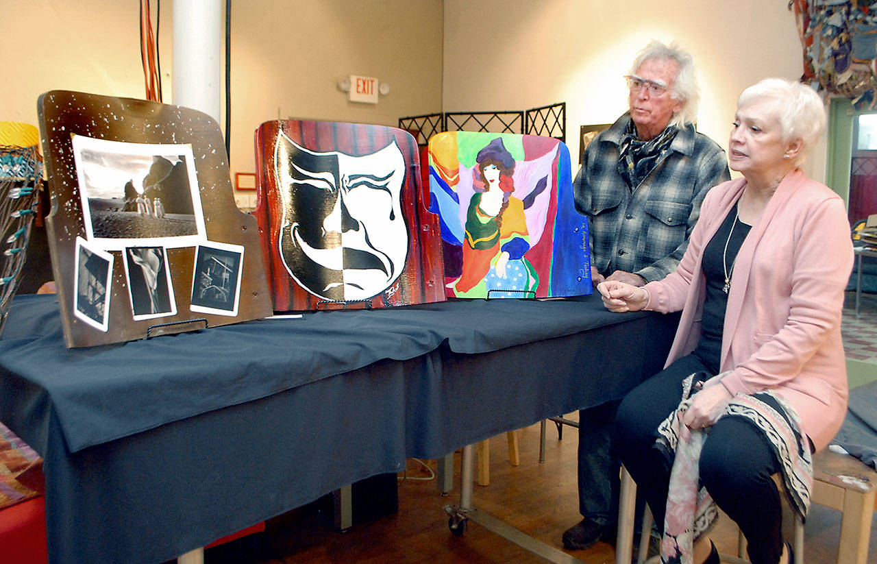 Port Angeles artist Bob Stokes, president of the Port Angeles Arts Council, and Kathy Balducci of the Port Angeles Community Players examine three decorated antique seat backs from the former Olympian Theater that will be auctioned off to benefit the players organization. (Keith Thorpe/Peninsula Daily News)