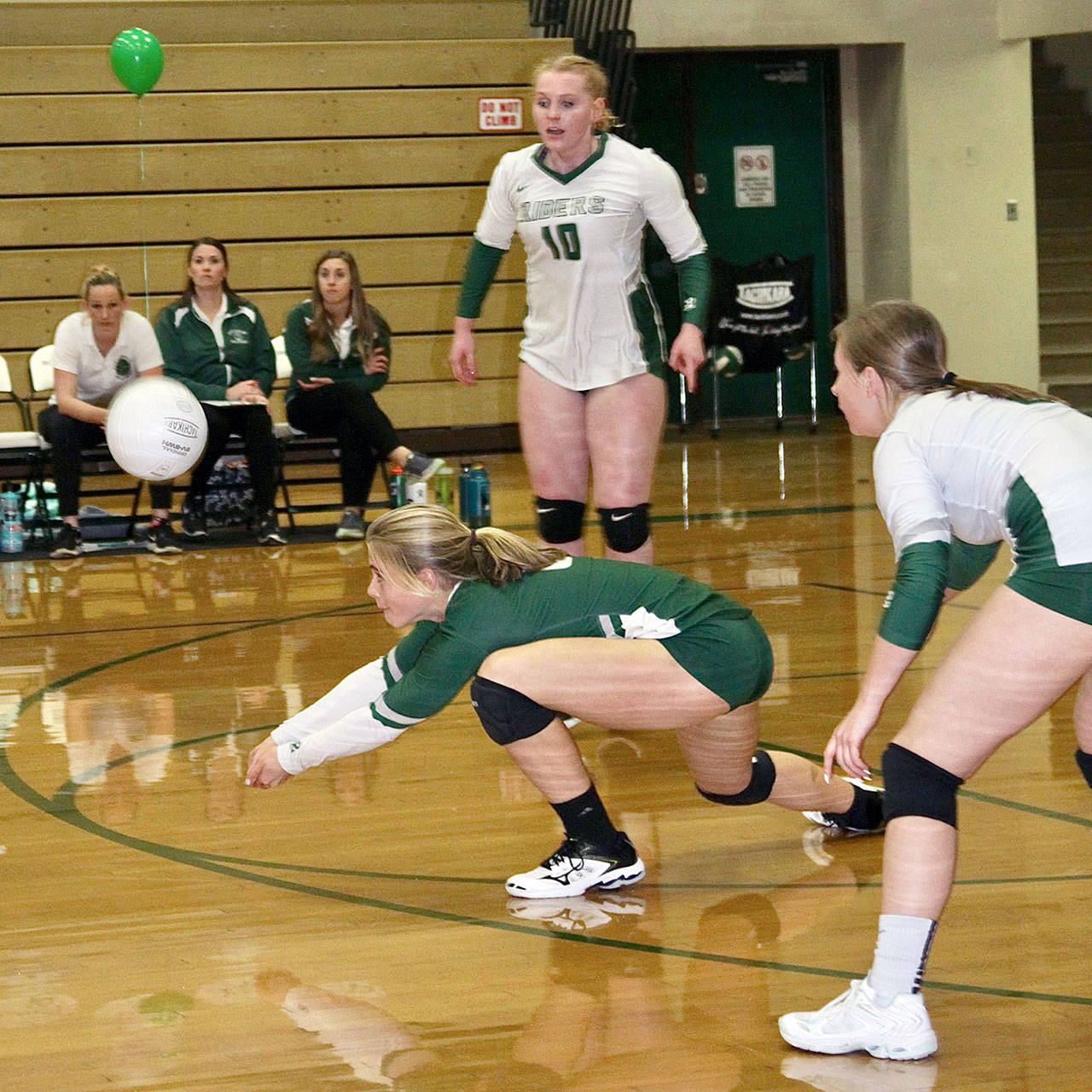 Port Angeles libero Lily Halberg digs a ball out against Olympic on Monday. The Riders took the Trojans to five games, but lost a close one as they prepare for the postseason. Teammate Kenndy Bruch (10) is in on the play. (Dave Logan/for Peninsula Daily News)