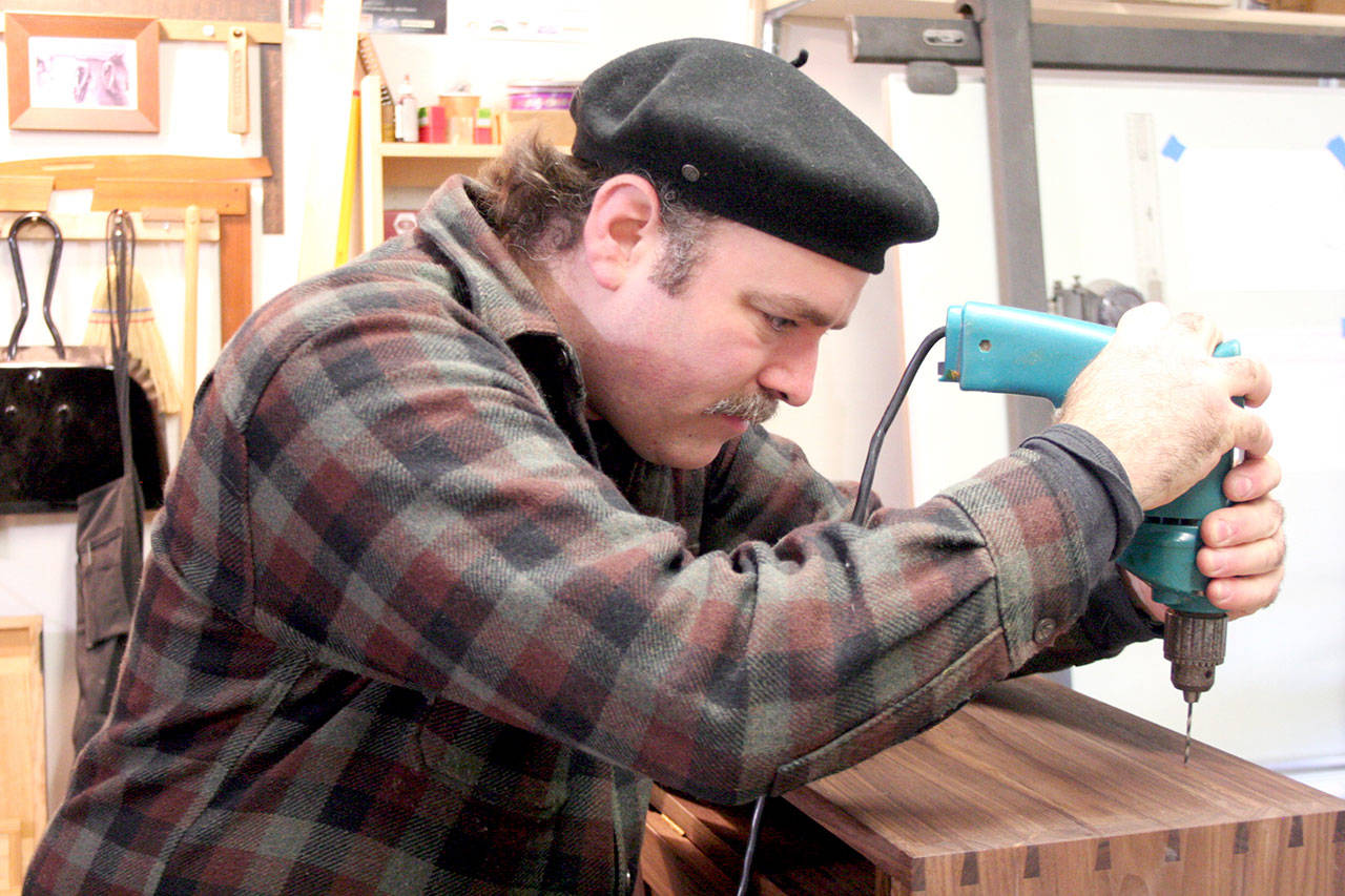 Matthew Straughn-Morse of Port Townsend uses a drill to start a hole for a screw on the top of a handmade secretary desk. Straughn-Morse will be one of several exhibitors this weekend at the Port Townsend Woodworkers Show, which will be held Saturday and Sunday at the American Legion Hall, 209 Monroe St. (Brian McLean/Peninsula Daily News)