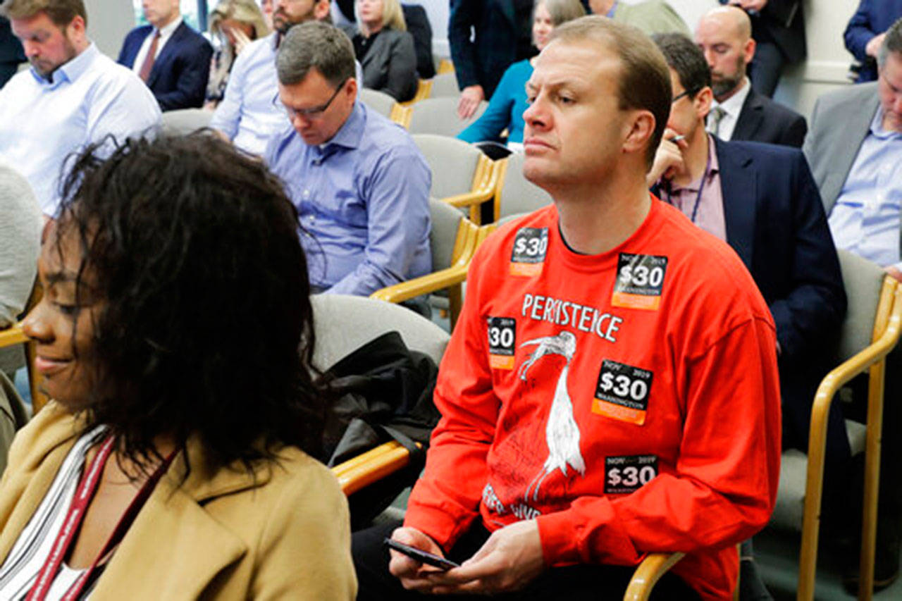Anti-tax activist Tim Eyman wears a sweatshirt with stickers from his I-976 $30 car tabs initiative on it as he attends the Associated Press Legislative Preview at the Capitol in Olympia on Jan. 10. (Ted S. Warren/Associated Press file)