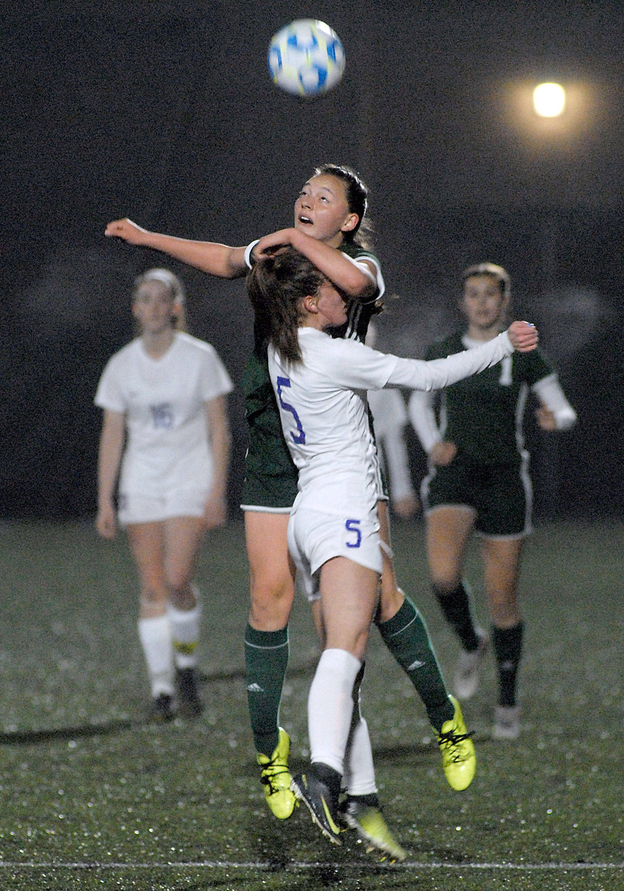 Port Angeles’ Jada Cargo, top, uses Sequim’s Mary McAleer for a boost to make the header during Saturday night’s seeding match at Wally Sigmar Field in Port Angeles. (Keith Thorpe/Peninsula Daily News)