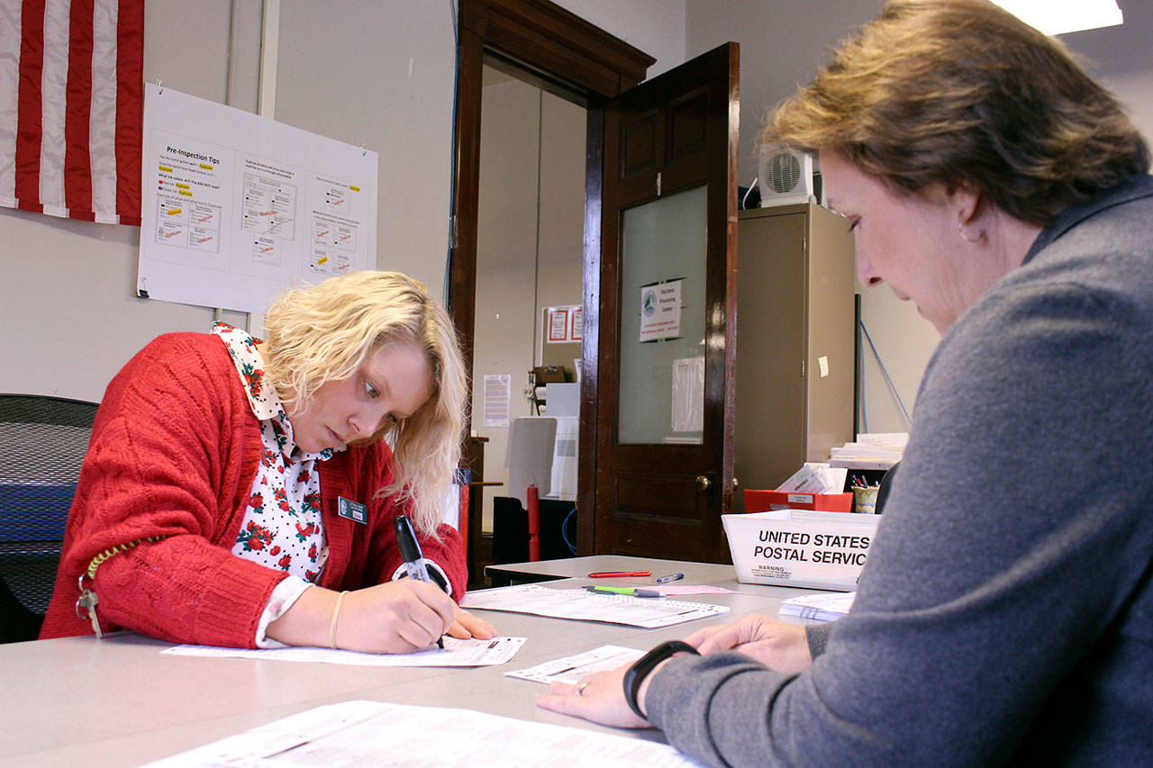 Jefferson County election coordinators Quinn Grewell, left, and Betty Johnson work to duplicate ballots that were damaged or had decisions crossed out and changed. The ballot answers are copied from the original ballot to a clean one, matching notated numbers, by a team of two. After the ballots are copied, an additional two people audit the work of the first team to guarantee accuracy. This process allows the ballot machine to correctly record the choices made by voters and the ballots “to be duplicated as the voters intended,” Johnson said. (Zach Jablonski/Peninsula Daily News)