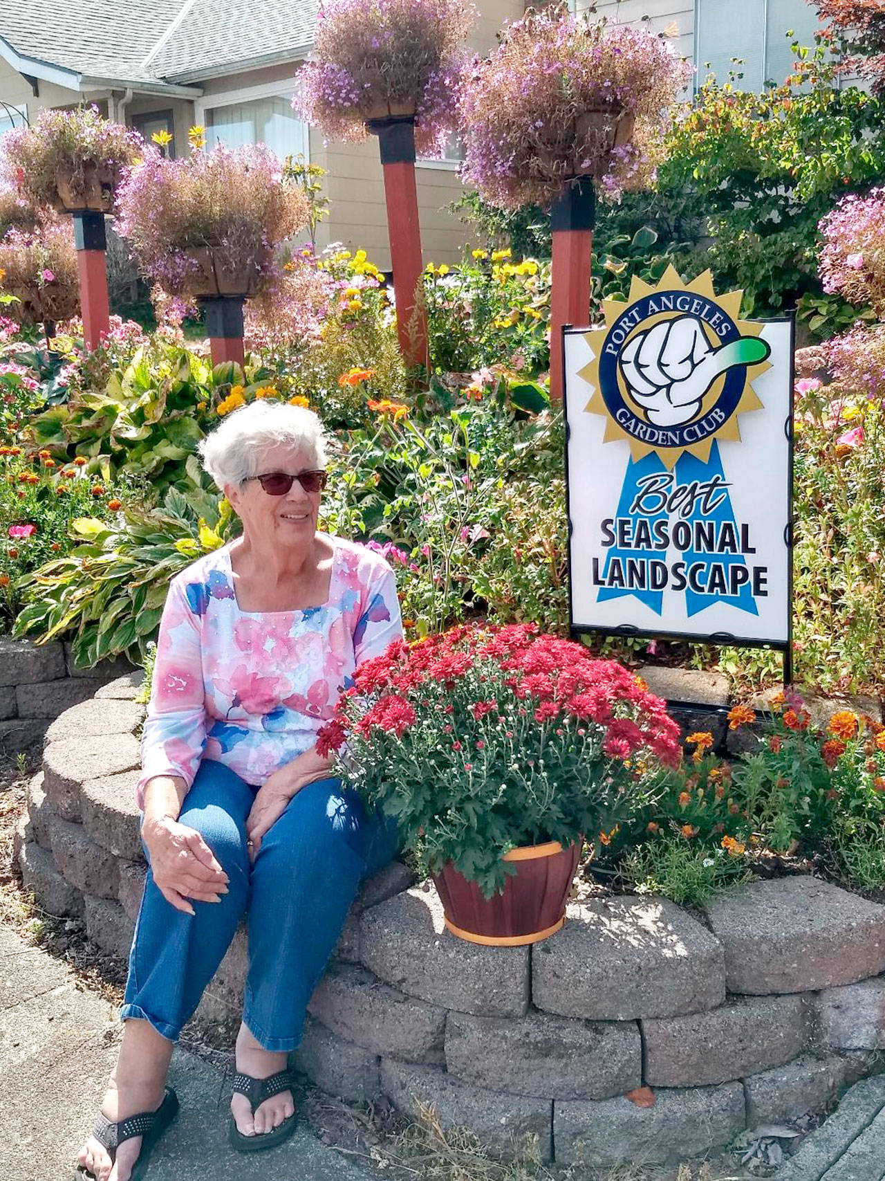 Judy Hubbard sits on a section of stone wall she built to retain flower beds.