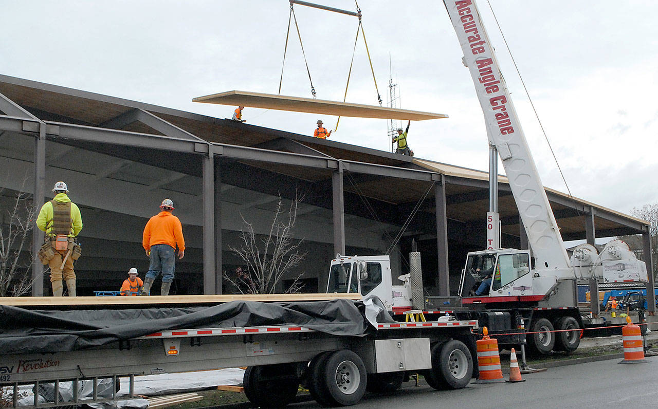A construction crane lowers a section of roof into position as crews maneuver it into place Tuesday at the Shore Aquatic Center in Port Angeles. (Keith Thorpe/Peninsula Daily News)