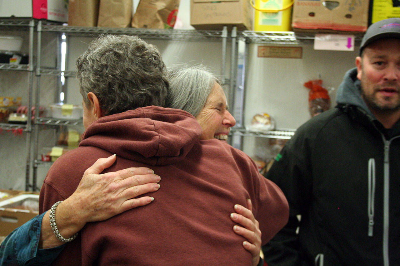 Ben Falge hugs Port Townsend Food Bank manager Shirley Moss on Monday. Moss also shared a hug with Arrow Lumber store manager Cadian Hendricks, right, after 375 turkeys were stacked in boxes by volunteers. (Brian McLean/Peninsula Daily News)