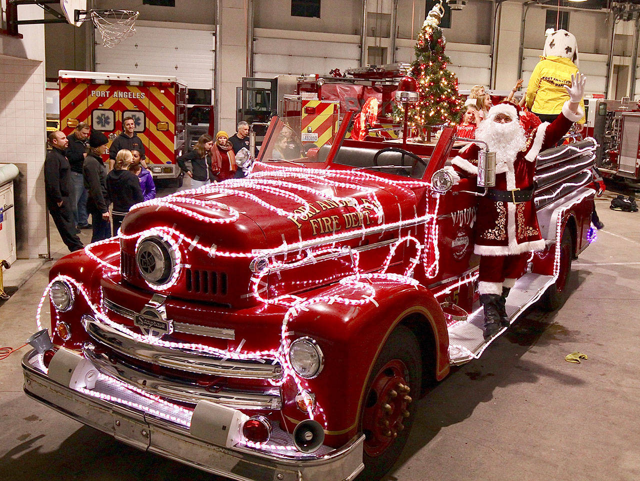 Firefighter Travis McFarland practices his Santa wave as the Port Angeles Fire Department’s 1956 Seagrave engine is decorated for Operation Candy Cane. (Dave Logan/for Peninsula Daily News)