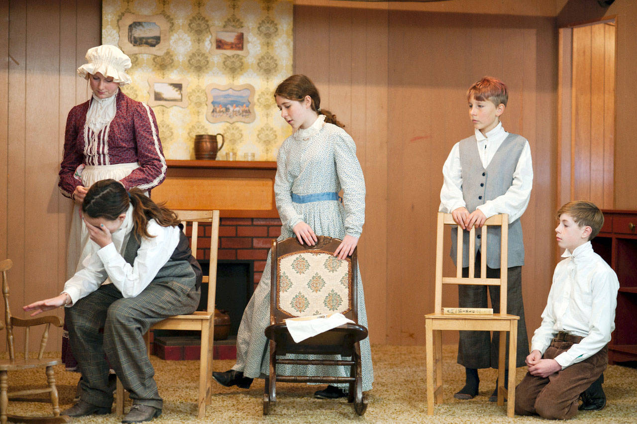 Wilhelmina Schmidt as Mrs. Cratchit and Charlotte Capel as Bob Cratchit, at right, are watched by the Cratchit children played by, from left, Zoe Guinan, Sage Harrington and Evan Kraft in “A Christmas Carol.” (Peirce Schmidt)