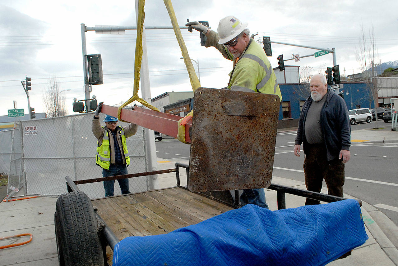 Port Angeles artist Gray Lucier, right, watches as Doug Joutsen, center, and Donn Frostad of M.A. Mortenson Co. lower Lucier’s sculpture “The Long Journey” onto a trailer Tuesday after being displaced from its display location at First and Oak streets to make way for construction of the Field Arts & Events Hall on the Port Angeles waterfront. (Keith Thorpe/Peninsula Daily News)