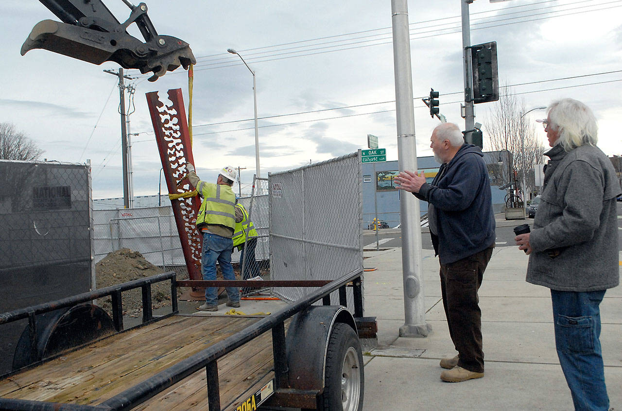 Port Angeles artists Gray Lucier and Bob Stokes, right, watch as Lucier’s sculpture “The Long Journey” is hoisted from its longstanding display location at First and Oak streets in downtown Port Angeles on Tuesday. (Keith Thorpe/Peninsula Daily News)
