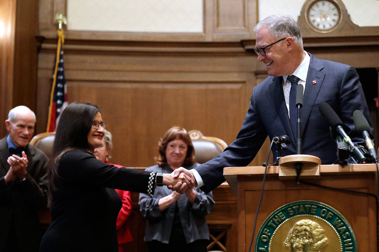 Whatcom County Superior Court Judge Raquel Montoya-Lewis, left, shakes hands with Gov. Jay Inslee after he introduced her as the newest member of the state Supreme Court on Wednesday in Olympia. (Elaine Thompson/The Associated Press)