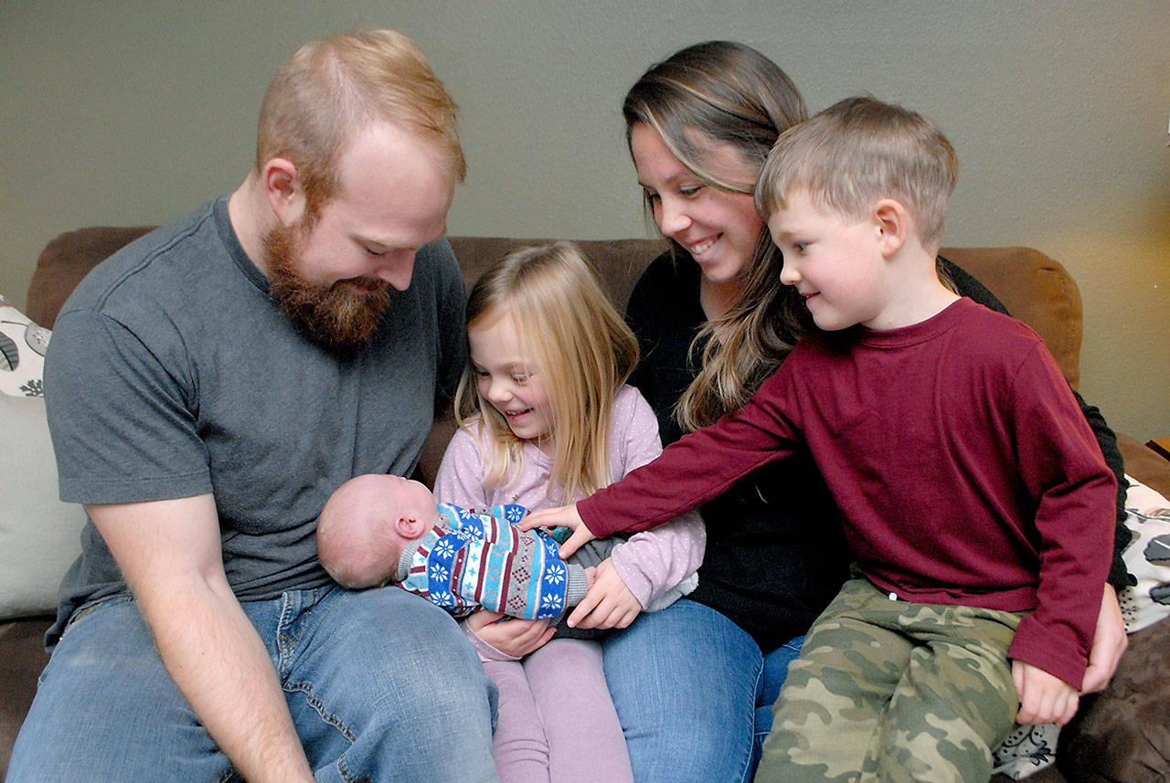 The Waldron family of Port Angeles, from left, Cortland, Addison, 6, Libby and Oliver, 3, look at their newest edition, Henry James Waldron, who was born in back of a vehicle on state Highway 20 in Jefferson County on Dec. 2. (Keith Thorpe/Peninsula Daily News)