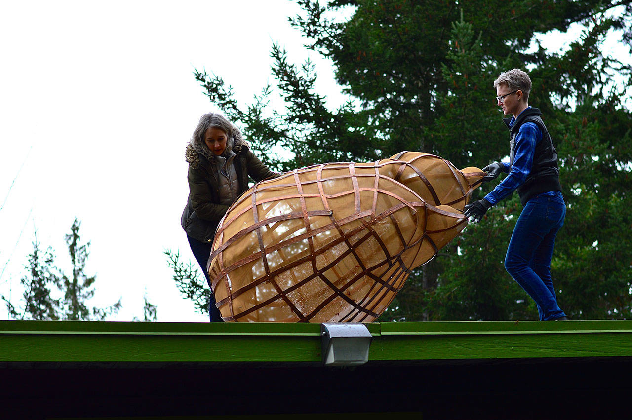 Sculptor Katherine Shaughnessy, left, works with Port Angeles Fine Arts Center’s Sarah Jane to move her creation, “Tempest-tost,” across the center’s roof. (Diane Urbani de la Paz/for Peninsula Daily News)