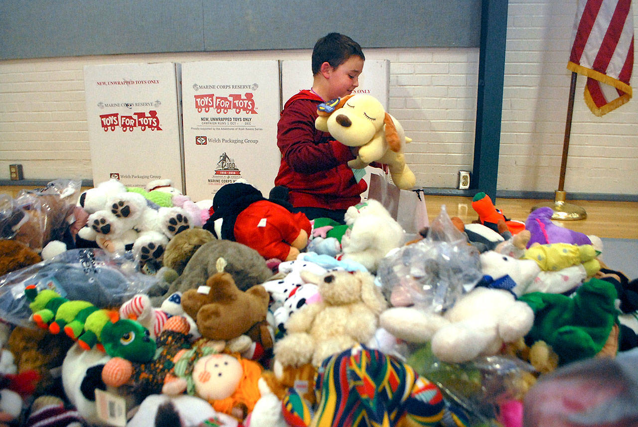 Taryn True, 8, picks out a toy dog to take home out of a pile of stuffed animals during the Christmas party for children of the Port Angeles unit of the Boys & Girls Clubs of the Olympic Peninsula. (Keith Thorpe/Peninsula Daily News)