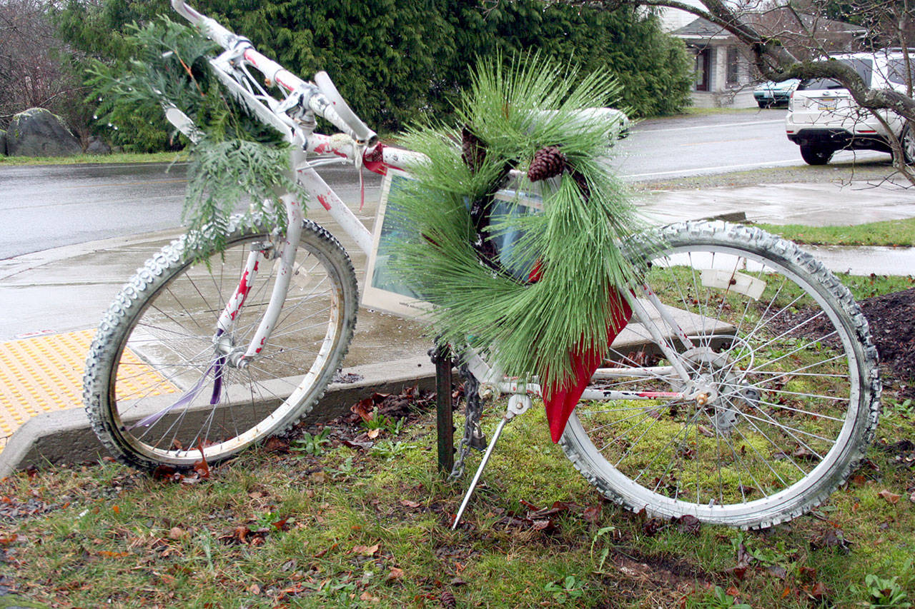 A white bicycle stands at the corner of 19th and Landes streets as a memorial for Marcus Henthorn, who died after he was struck in the intersection by a car driven by Patrick Cleon McConnell of Port Townsend in March 2018. A photo of Henthorn is underneath a wreath. (Brian McLean/Peninsula Daily News)