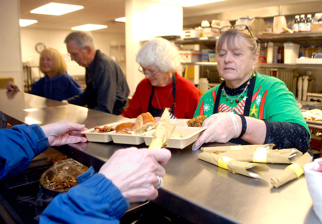 Linda Crabb of Sequim, right, serves a Christmas Eve lunch at the Salvation Army kitchen in Port Angeles with the help of fellow volunteers, from left, Phyllis Meyer of Sequim and Tom and Ann Allen of Port Angeles. (Keith Thorpe/Peninsula Daily News)