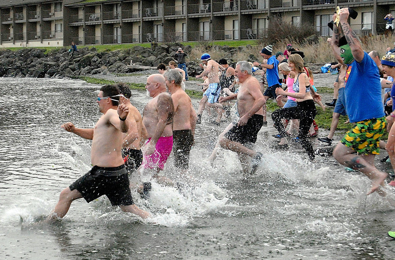 Polar Bear Dip participants race into the chilly waters at Port Angeles Harbor’s Hollywood Beach on New Year’s Day in 2019. (Keith Thorpe/Peninsula Daily News)