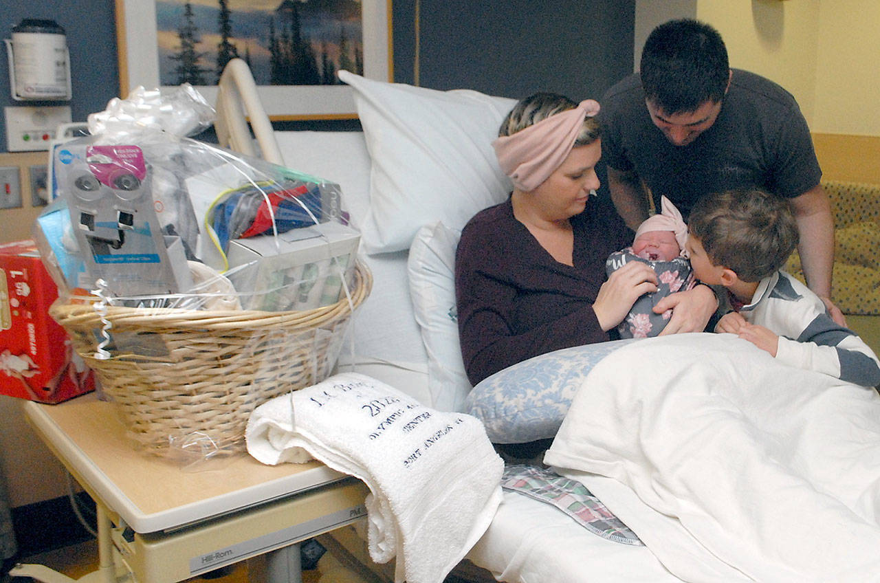 Olympic Medical Center Foundation presented a gift basket filled with infant care items, along with a commemorative towel, to the Lee Family on Wednesday. (Keith Thorpe/Peninsula Daily News)