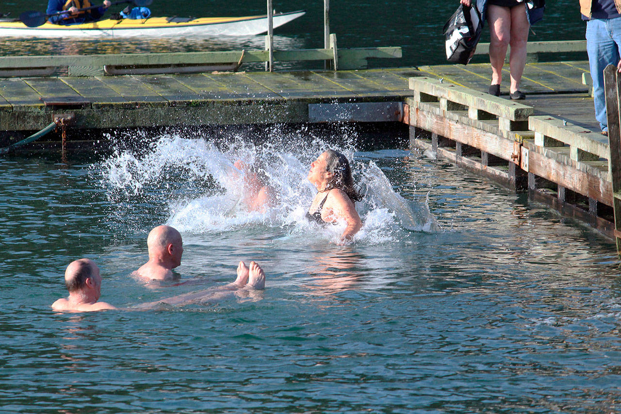 Laurel Dawson lands in the water next to her husband during the Nordland Polar Plunge on Wednesday. The pair jumped in for the first time as a token of solidarity with their daughter who is in Antarctica studying climate change. (Zach Jablonski/Peninsula Daily News)