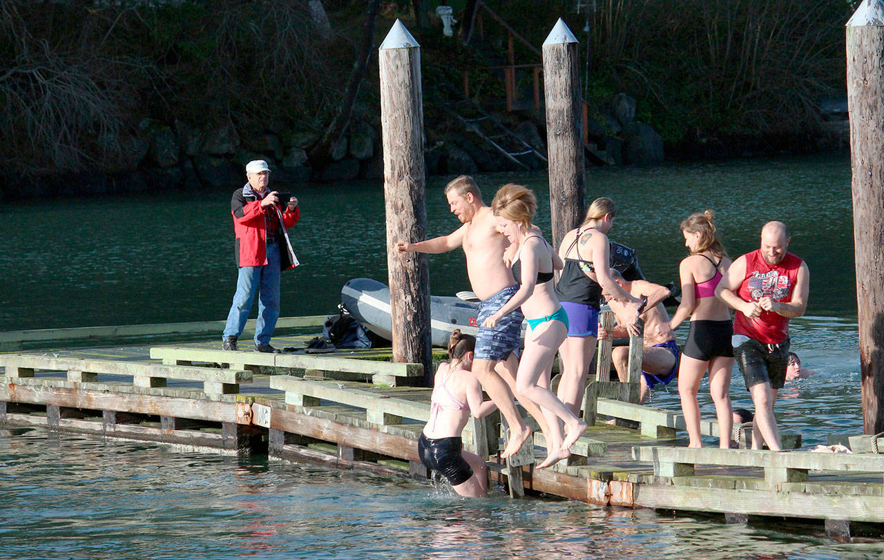 Two participants in the Nordland Polar Plunge jump off the dock in front of the Nordland General Store on Wednesday afternoon to celebrate the new year. (Zach Jablonski/Peninsula Daily News)