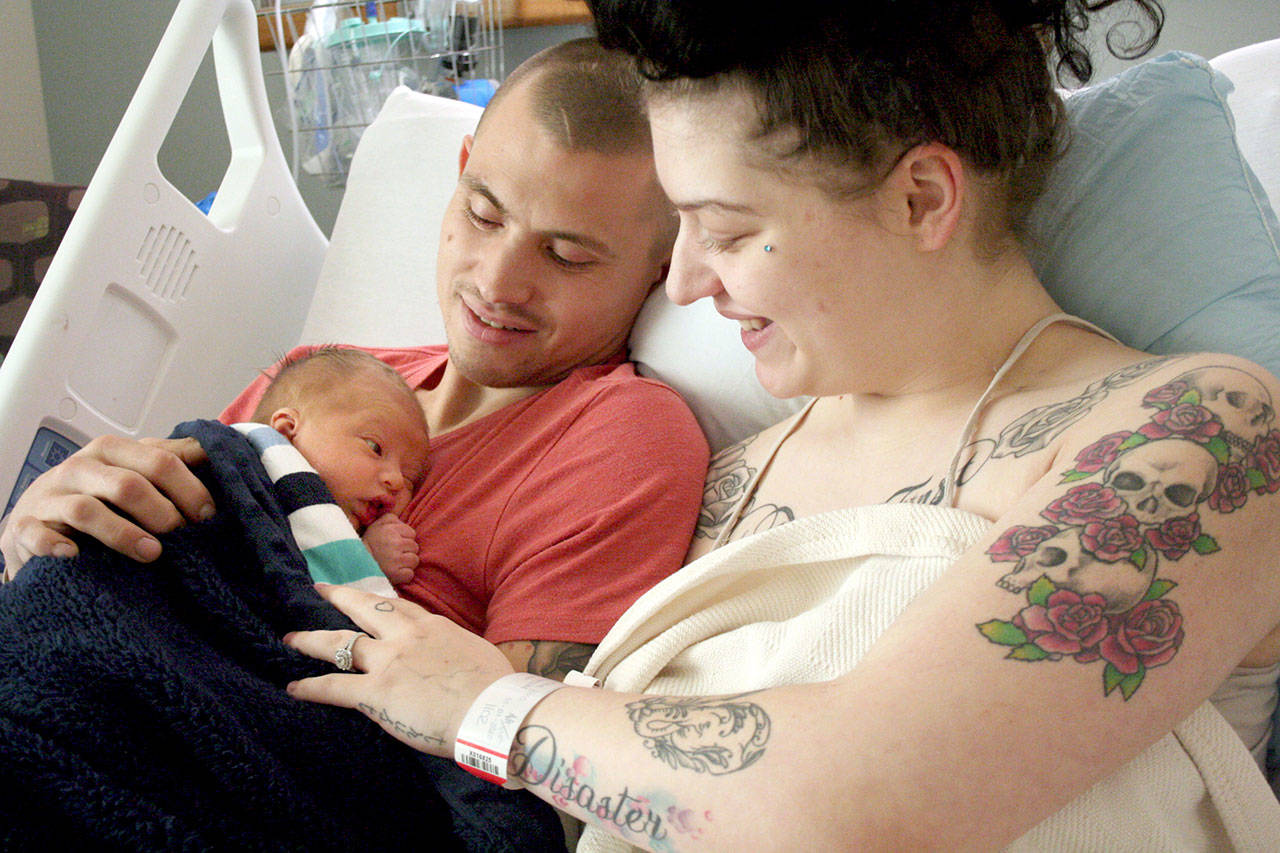 Casey McConaghy, left, holds his son, Mason Matthew McConaghy, next to his fiancée, Karma Hos, inside their room in the family birthing center at Jefferson Healthcare hospital. Mason was the first baby born in Jefferson County when he arrived six days early at 1:23 p.m. Jan. 1. (Brian McLean/Peninsula Daily News)
