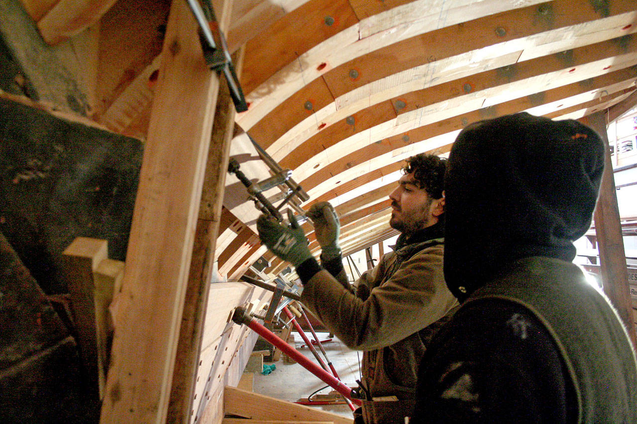 Jordan Bard, left, and Greg Friedrichs tighten a board into place on the Western Flyer. (Brian McLean/Peninsula Daily News)