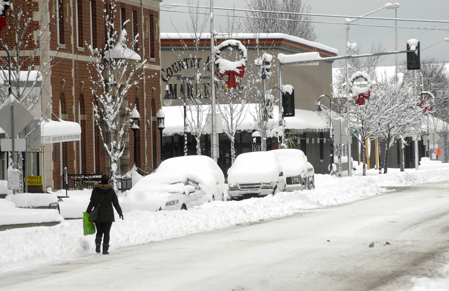 A pedestrian makes her way along a snow-covered Front Street in downtown Port Angeles on Wednesday after heavy snow blanketed the city overnight. (Keith Thorpe/Peninsula Daily News)