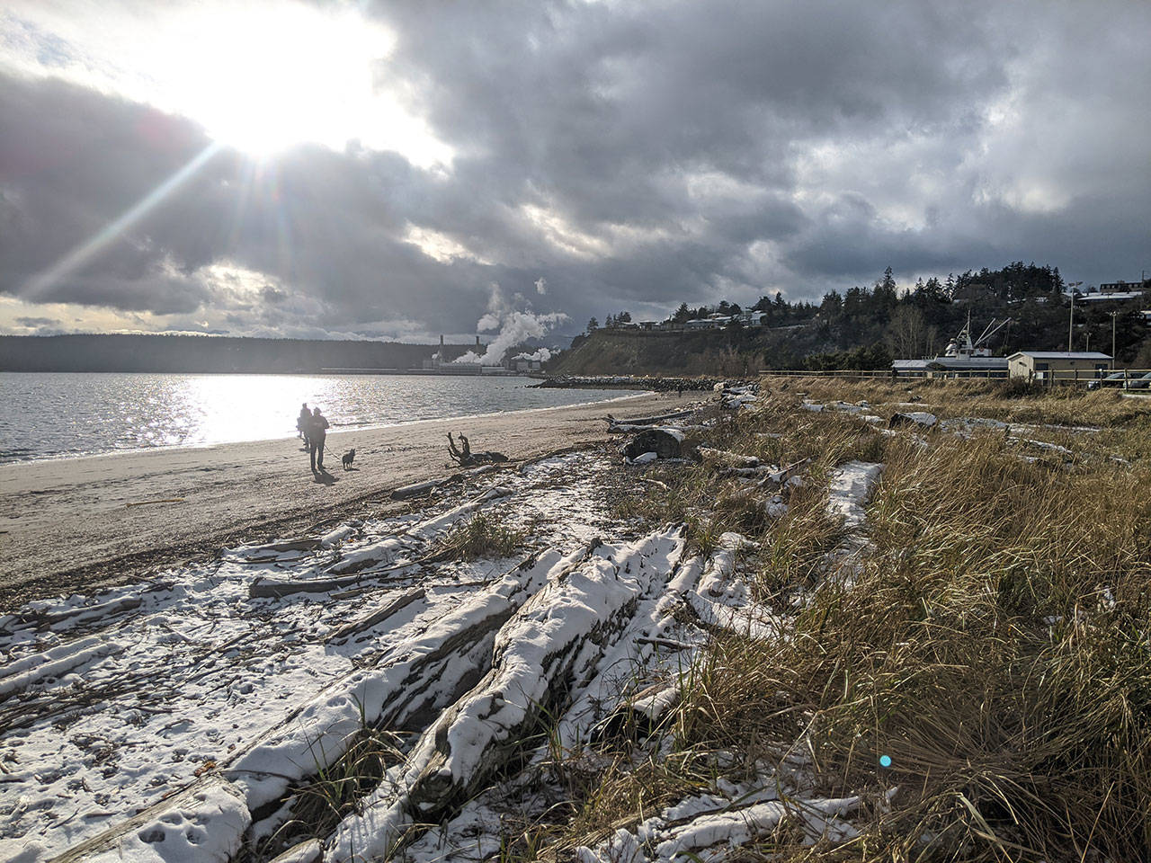 Residents enjoy the sun and snow as they walked along the beach near Boat Haven Marina in Port Townsend on Tuesday afternoon. (Zach Jablonski/Peninsula Daily News)