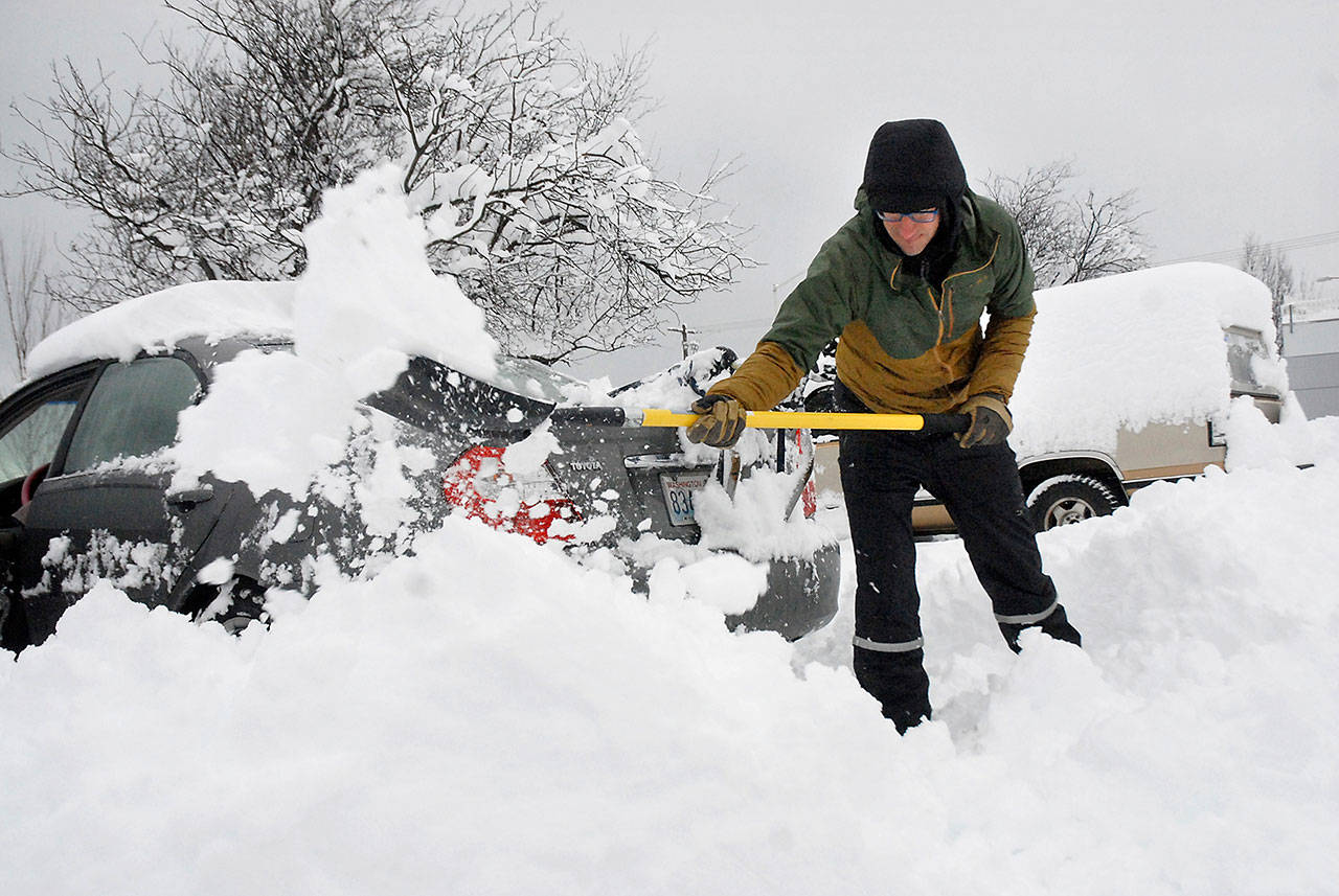 Curt Haugen of Sequim shovels heavy snow to free up a friend’s car trapped in the public parking lot in the 200 block of East Front Street in downtown Port Angeles on Wednesday. (Keith Thorpe/Peninsula Daily News)