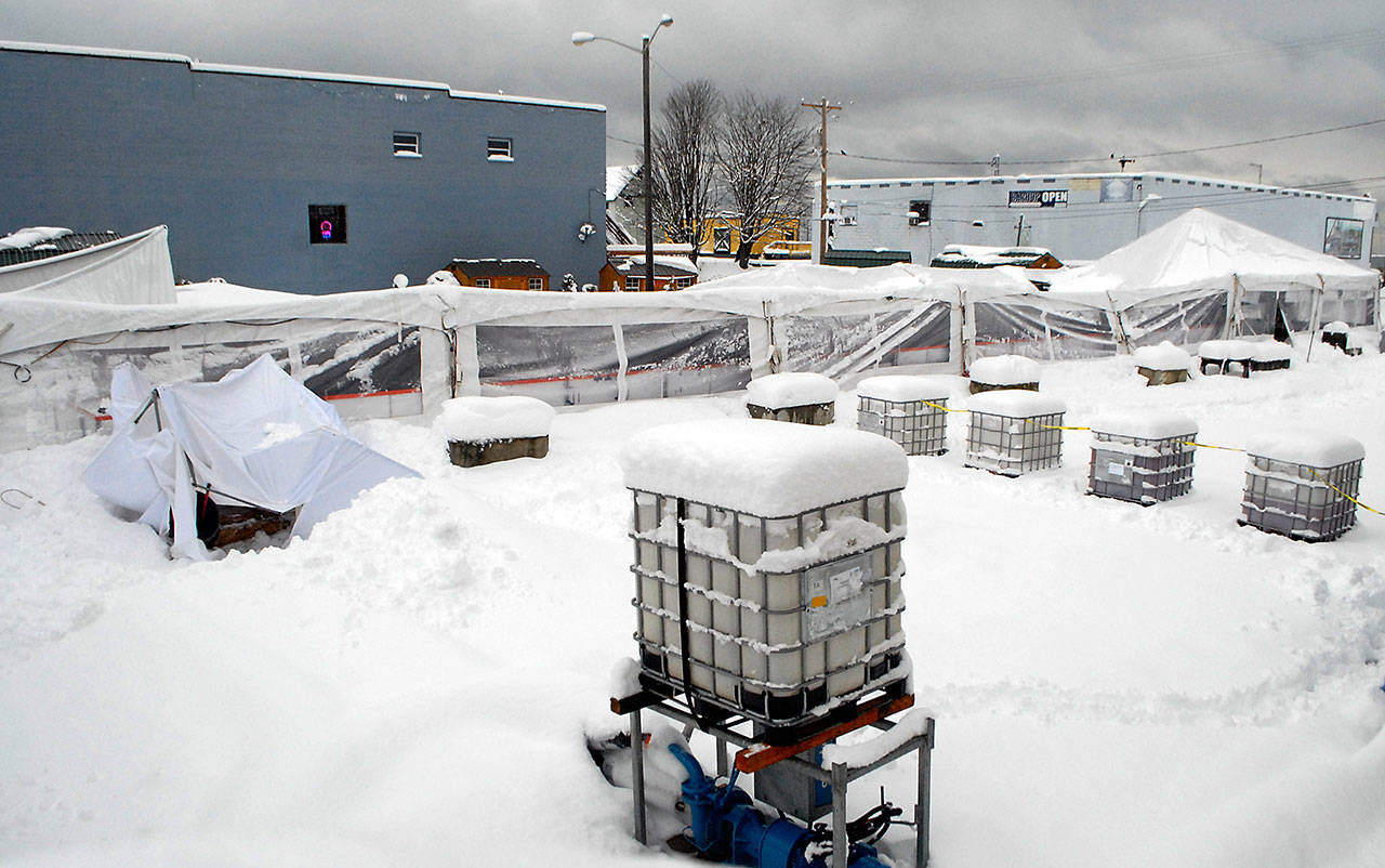 Heavy snow covers ice-making equipment next to the collapsed tent that once covered the skating rink of the Port Angeles Winter Ice Village on Wednesday morning. (Keith Thorpe/Peninsula Daily News)