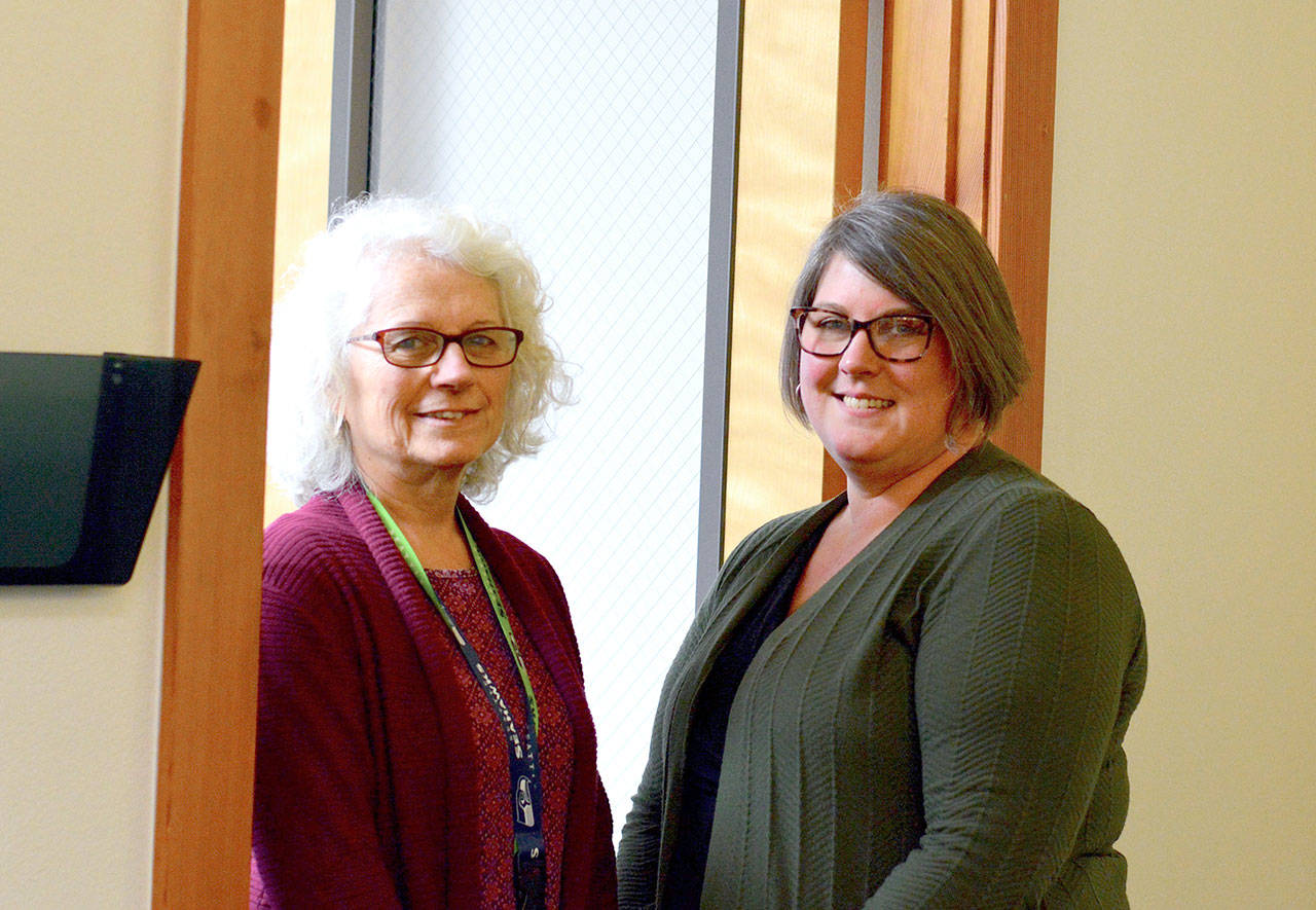 OlyCAP office coordinator Kathy Sculley, left, and community services director Marki Lockhart welcome volunteers in the Port Angeles office. (Diane Urbani de la Paz/for Peninsula Daily News)