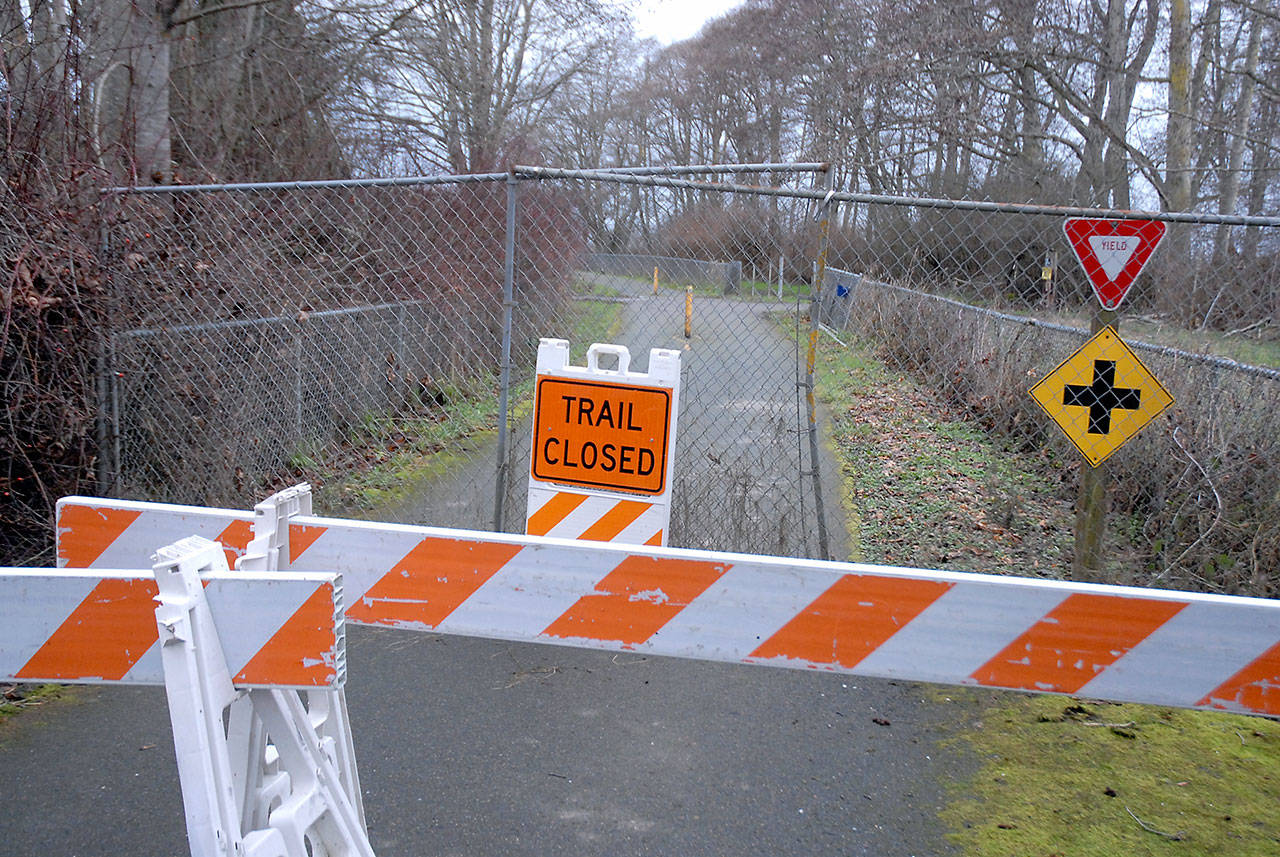Barricades, construction fencing and a warning sign block a section of the Olympic Discovery Trail near Four Seasons Ranch east of Port Angeles near the site where human remains were discovered near a storm-damaged portion of the trail. (Keith Thorpe/Peninsula Daily News)