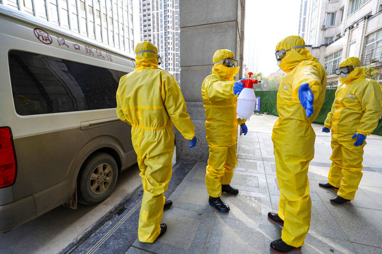Funeral workers disinfect themselves after handling a virus victim in Wuhan in central China’s Hubei Province, Thursday, Jan. 30, 2020. China counted 170 deaths from a new virus Thursday and more countries reported infections, including some spread locally, as foreign evacuees from China’s worst-hit region returned home to medical observation and even isolation. (Chinatopix via AP)