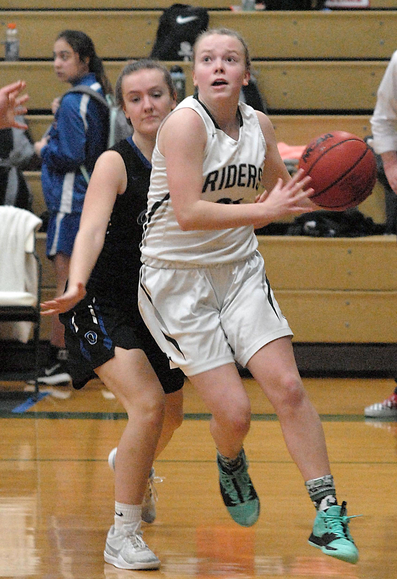 Keith Thorpe/Peninsula Daily News Anna Petty of Port Angeles, right, drives to the lane defended by Olympics Elisa Turnquist on Friday at Port Angeles High School.