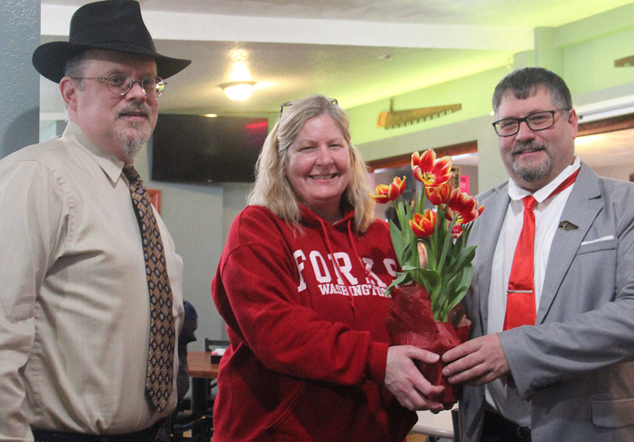 Forks Chamber of Commerce Director Lissy Andros presents Mayor Tim Fletcher with some tulips after his State of the City address. Forks city attorney/planner Rod Fleck, at left, also spoke. (Christi Baron/Olympic Peninsula News Group)