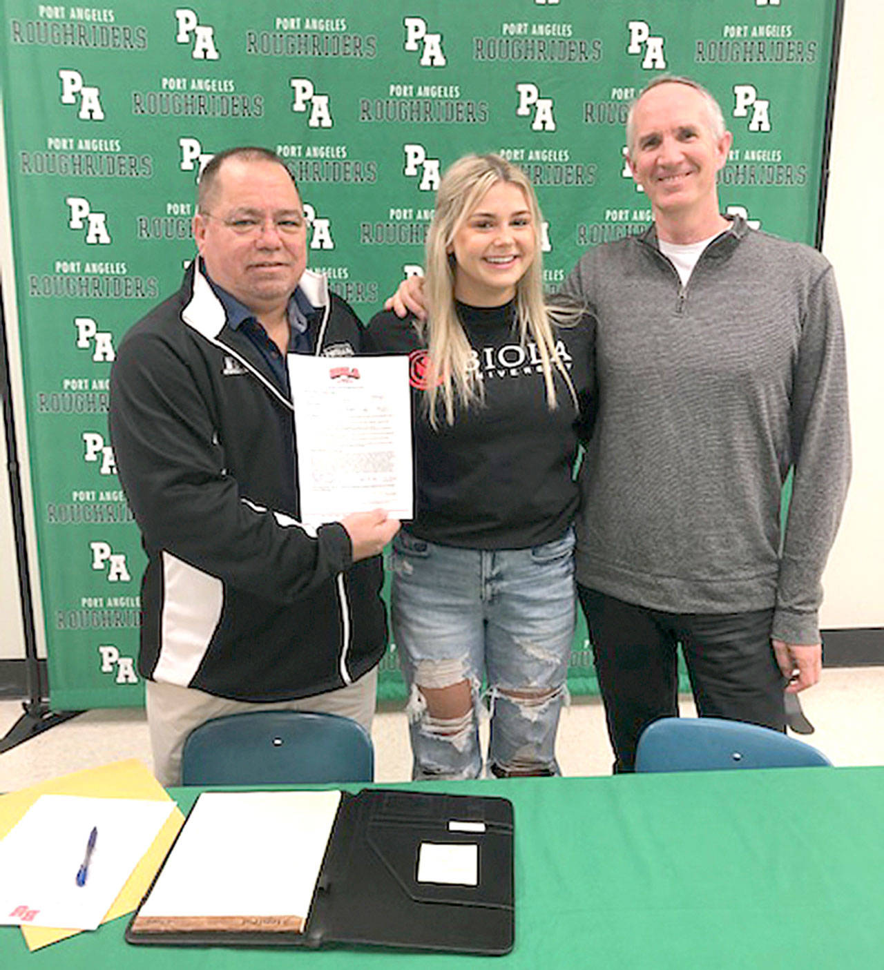 Kenzie Johnson signs to swim for Biola University in Southern California. Johnson placed several times at state for the Roughriders and won a state relay championship her freshman year at Port Angeles. At left is Port Angeles Athletic Director Dwayne Johnson and at right is Port Angeles Girls Swim Coach Britt Hemphill.