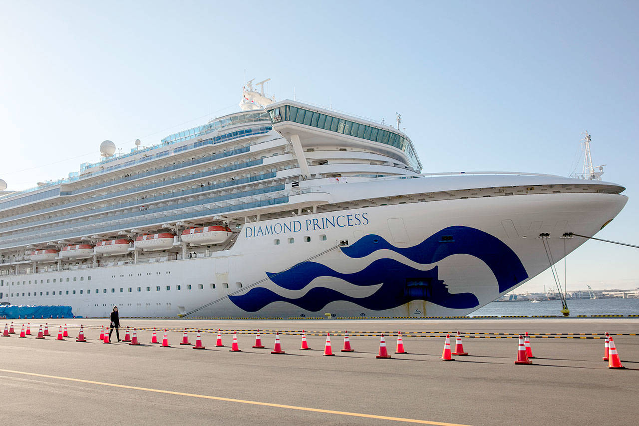 A reporter walks near the quarantined Diamond Princess cruise ship in Yokohama near Tokyo on Tuesday, Feb. 11, 2020. Japan’s Health Minister Katsunobu Kato said the government was considering testing everyone remaining on board and crew on the Diamond Princess, which would require them to remain aboard until results were available. (Jae C. Hong/The Associated Press)