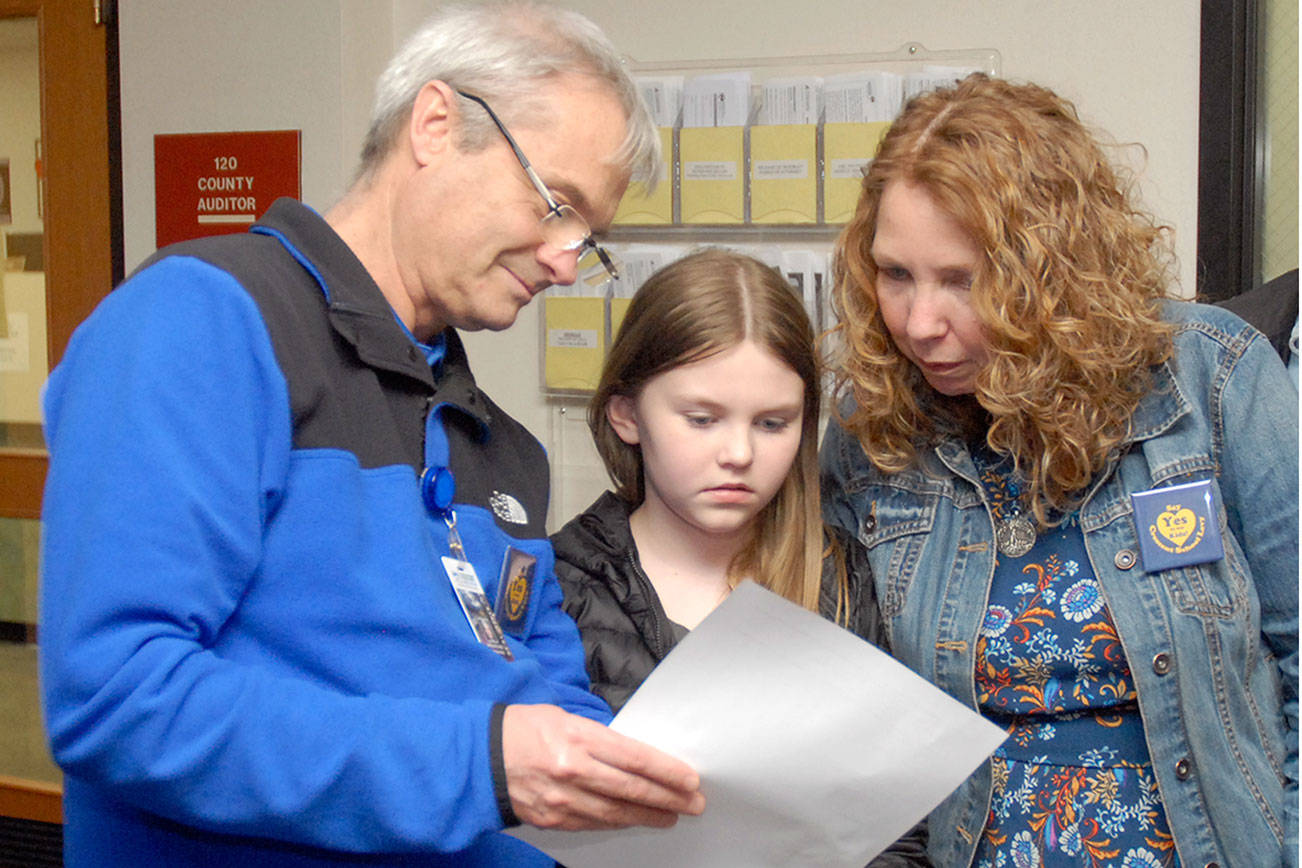 Crescent School Superintendent Dave Bingham, left, looks over election results with school board member Susan Hopper and her daughter, Mariah Hopper, 10, on Tuesday night at the Clallam County Courthouse. (Keith Thorpe/Peninsula Daily News)