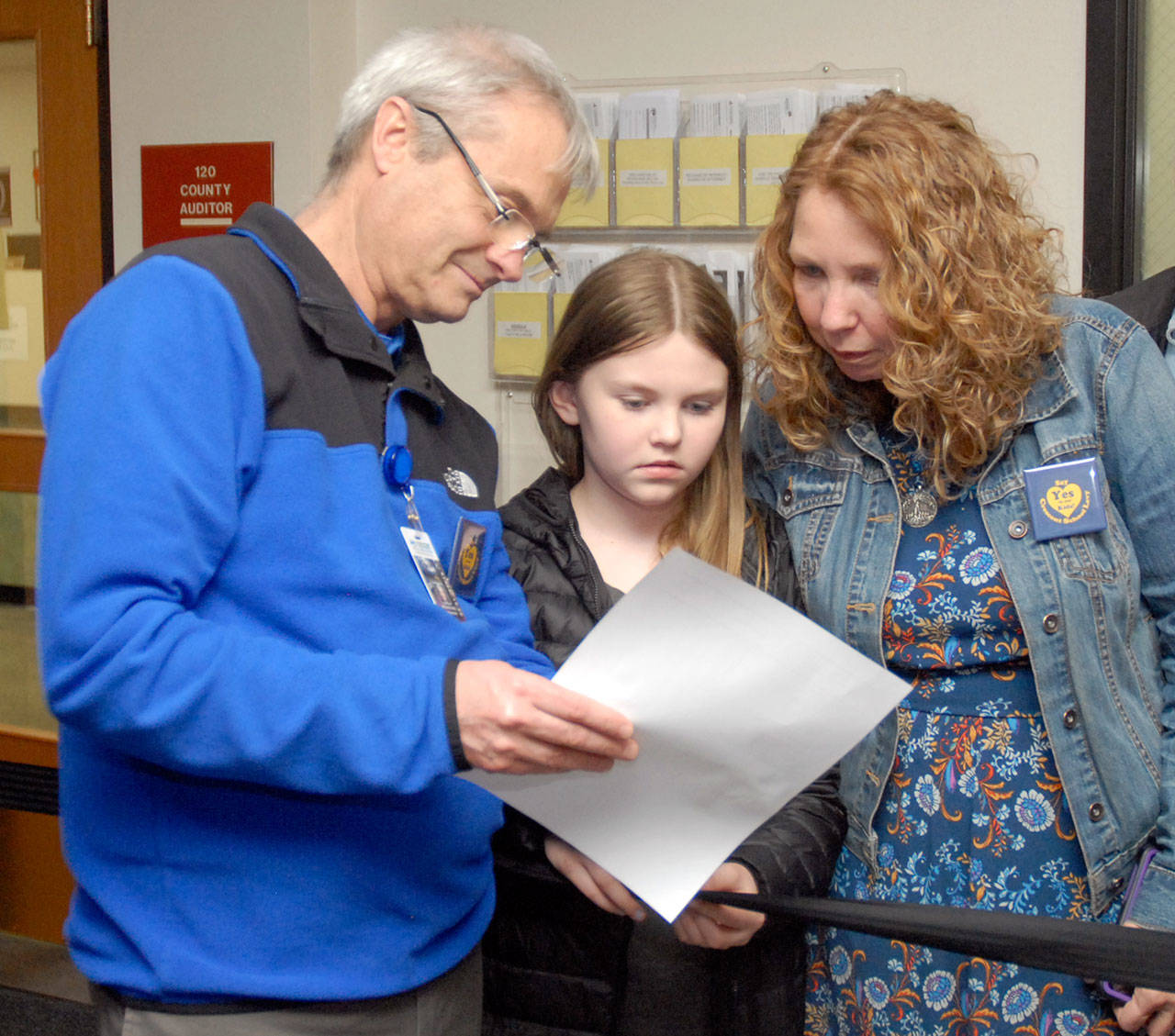 Crescent School Superintendent Dave Bingham, left, looks over election results with school board member Susan Hopper and her daughter, Mariah Hopper, 10, Tuesday night at the Clallam County Courthouse. (Keith Thorpe/Peninsula Daily News)