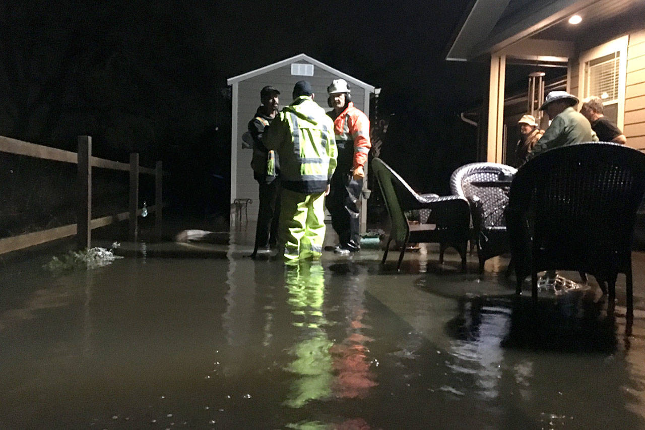 City of Sequim staff consult last week about options to resolve flooding issues off Rolling Hills Way in Sequim. Crews brought in a pump and sandbags to take out and keep water out of the home’s crawlspace. (Matthew Nash /Olympic Peninsula News Group)