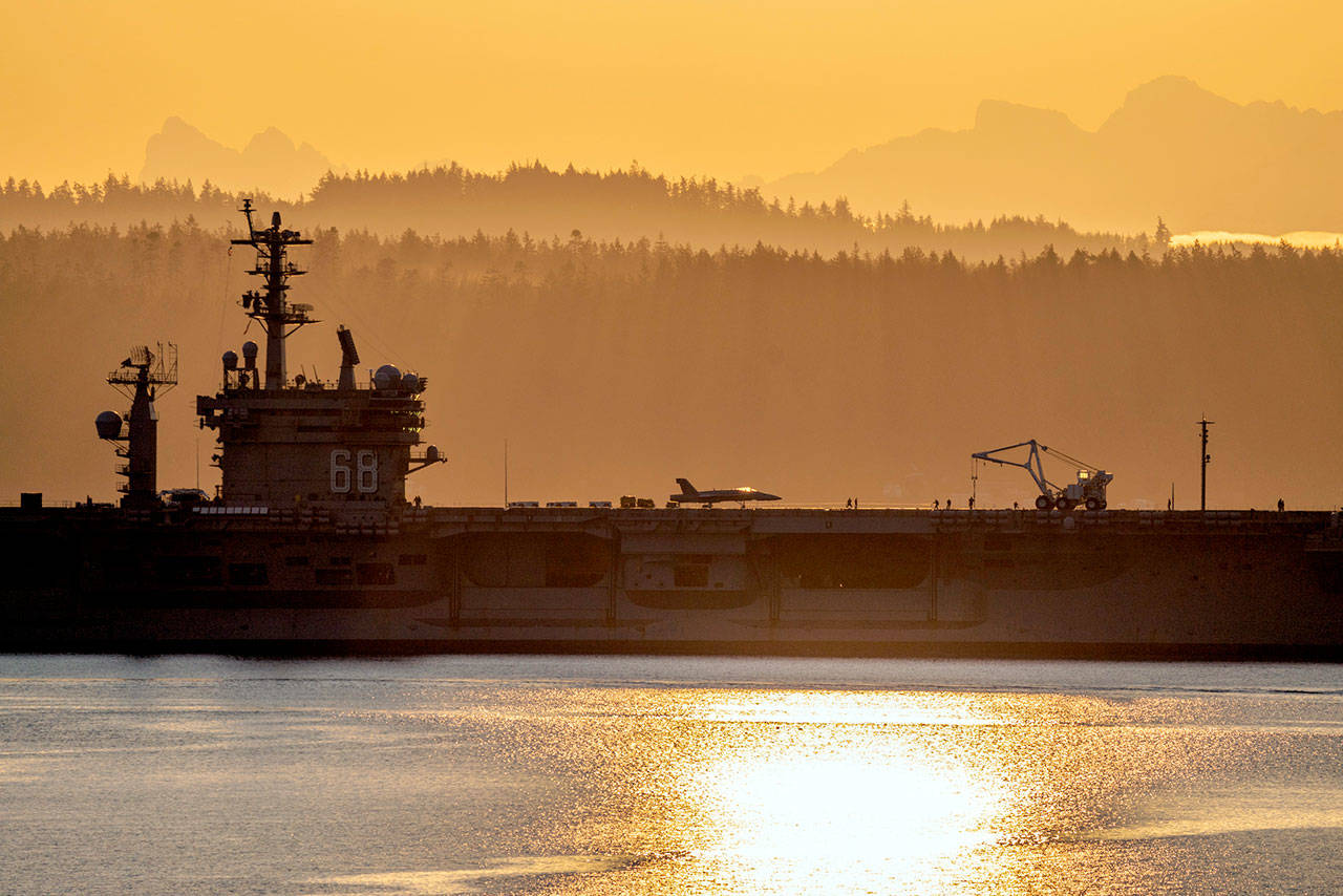 A Navy jet fighter sits at the ready as the USS Nimitz (CVN 68) approaches Naval Magazine Indian Island, located at the south end of Port Townsend Bay, just after sunrise Tuesday. (Steve Mullensky/for Peninsula Daily News)
