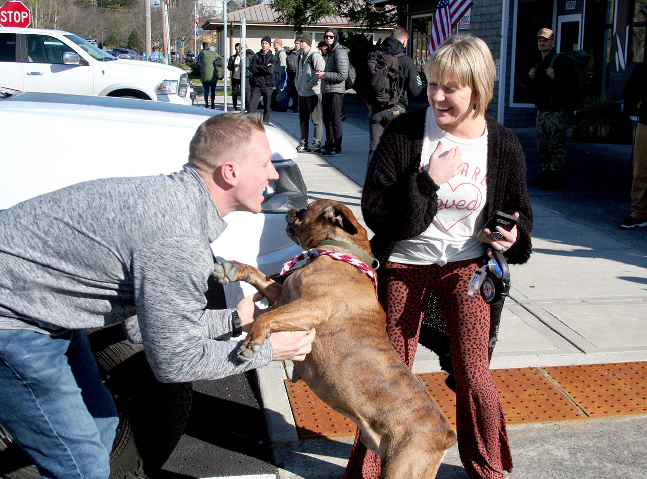 U.S. Navy Lt. Julian Krusely, left, is welcomed by his dog, Cash, and his wife, Kate, as he steps off a bus Tuesday. Sailors from the USS Nimitz will be in Port Townsend through Thursday, and they will be on buses traveling from Naval Magazine Indian Island. (Brian McLean/Peninsula Daily News)