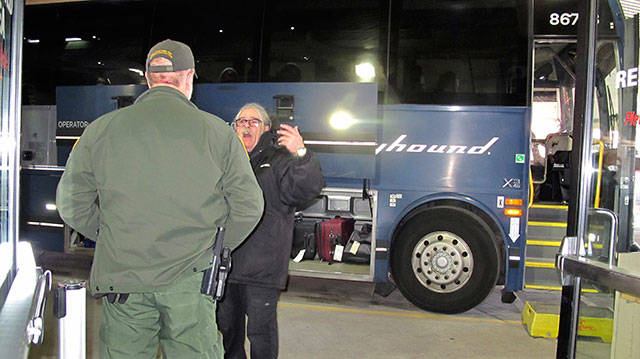 In this Thursday, Feb. 13, 2020, photo, a worker, right, speaks with a Customs and Border Protection agent seeking to board a Greyhound bus headed for Portland, Ore., at the Spokane Intermodal Center, a terminal for buses and Amtrak in Spokane. (Nicholas K. Geranios/The Associated Press)